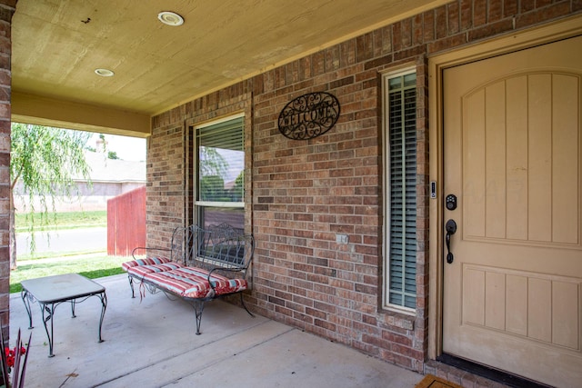 view of exterior entry featuring brick siding and covered porch