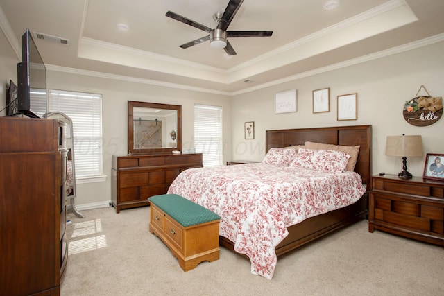 bedroom with a raised ceiling, visible vents, a ceiling fan, light carpet, and crown molding