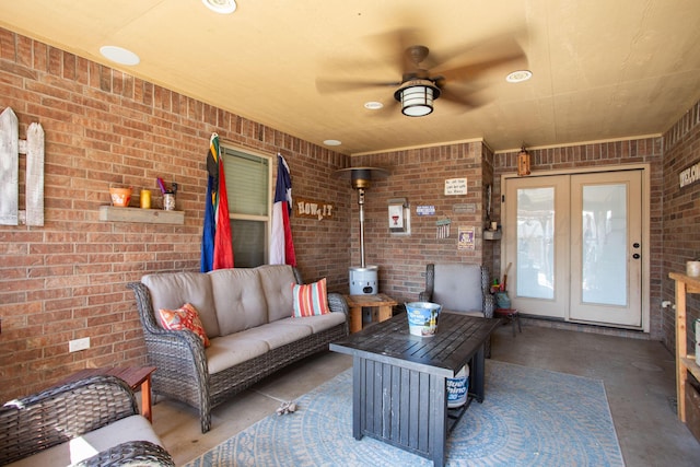 living room featuring ceiling fan, brick wall, and a wood stove