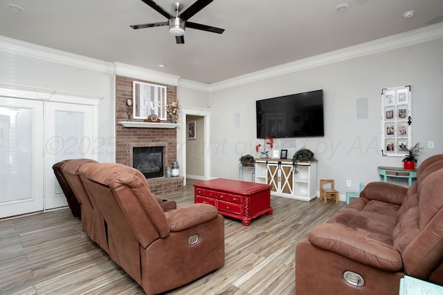 living area featuring light wood-type flooring, a brick fireplace, crown molding, and ceiling fan