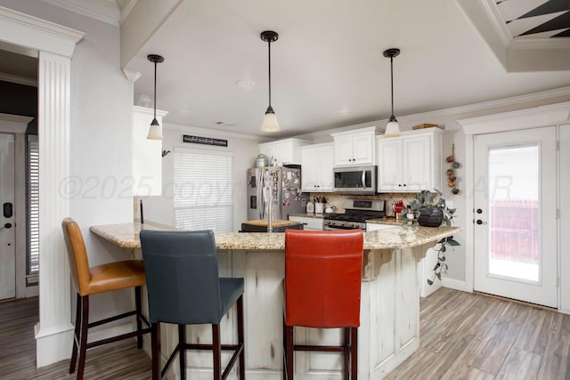 kitchen featuring decorative backsplash, a breakfast bar area, stainless steel appliances, light wood-style flooring, and a peninsula