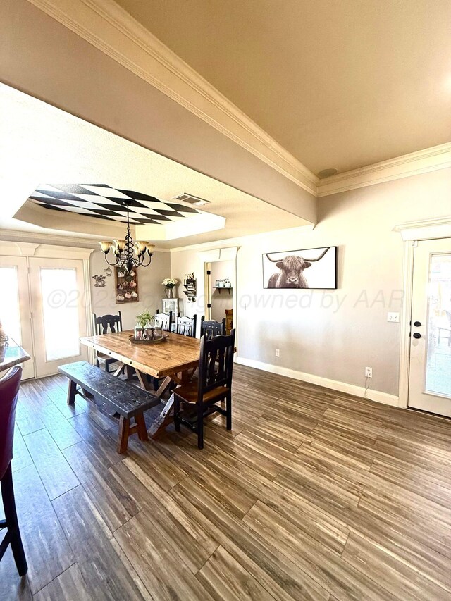 dining room with baseboards, visible vents, an inviting chandelier, wood finished floors, and ornamental molding