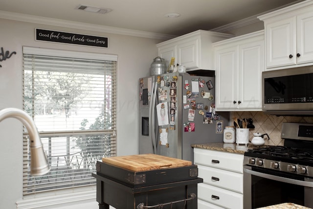 kitchen featuring white cabinets, stainless steel appliances, visible vents, ornamental molding, and decorative backsplash