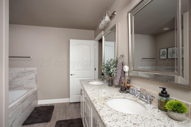 bathroom featuring hardwood / wood-style flooring, tiled tub, and vanity