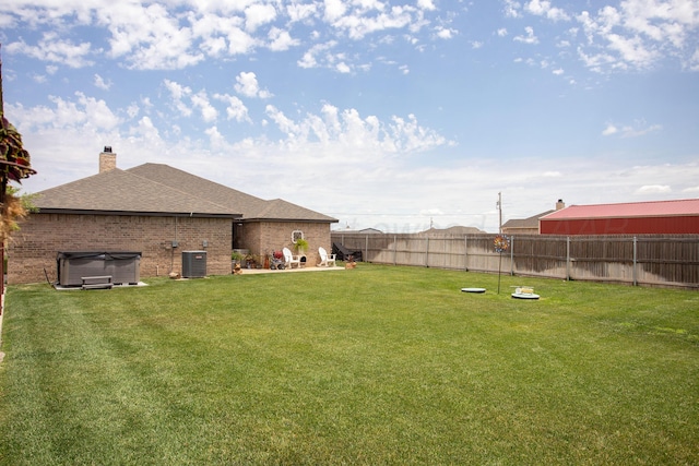 view of yard with central AC unit and a hot tub