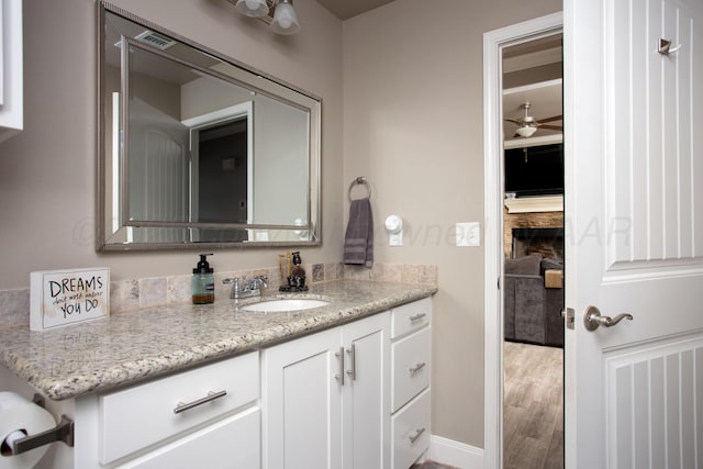 bathroom with hardwood / wood-style floors, ceiling fan, and vanity