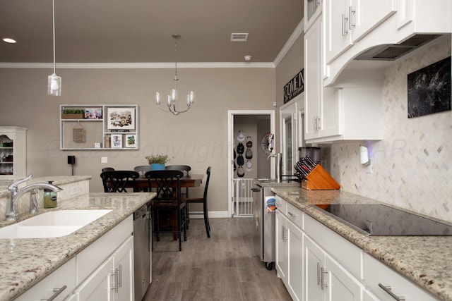 kitchen with black electric stovetop, a notable chandelier, ornamental molding, sink, and white cabinetry