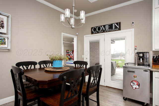 dining area with ornamental molding, a notable chandelier, and light hardwood / wood-style flooring