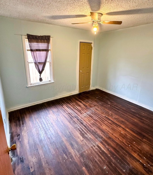 empty room with ceiling fan, dark hardwood / wood-style floors, and a textured ceiling