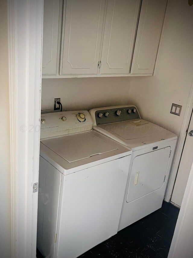 clothes washing area with separate washer and dryer and cabinets