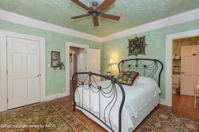 bedroom with dark wood-type flooring, ensuite bathroom, ceiling fan, and ornamental molding