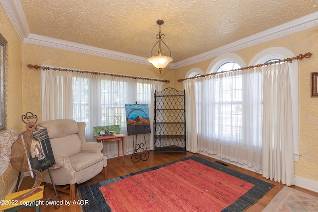 sitting room with hardwood / wood-style floors, a textured ceiling, and crown molding