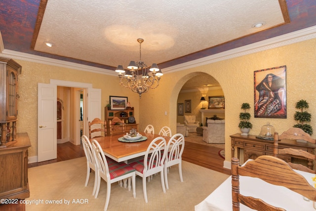 dining room with a textured ceiling, light hardwood / wood-style flooring, and crown molding