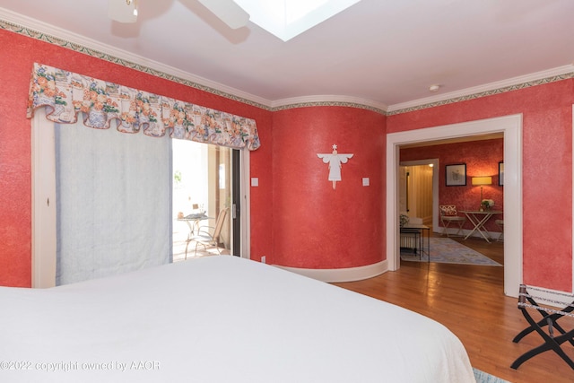 bedroom featuring hardwood / wood-style flooring, ceiling fan, a skylight, and crown molding