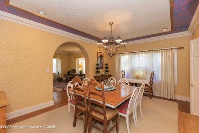1607 S Harrison St, Amarillo, TX 79102 - dining space with arched walkways, a textured wall, crown molding, a textured ceiling, and light wood-type flooring