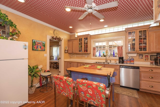 kitchen featuring sink, ornamental molding, dark hardwood / wood-style floors, stainless steel dishwasher, and white refrigerator