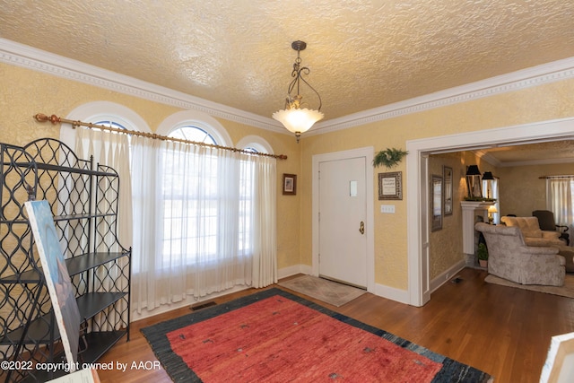 foyer featuring ornamental molding, wood-type flooring, and a textured ceiling