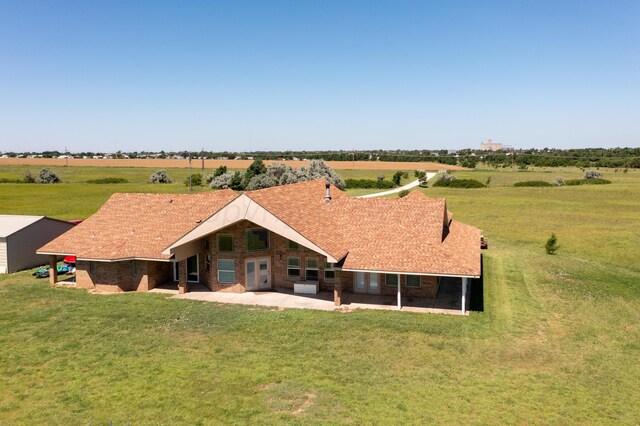 rear view of house featuring a yard and a rural view