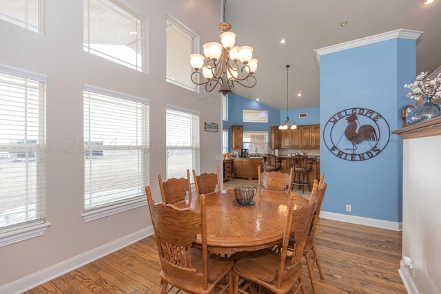 dining space with light wood-type flooring, high vaulted ceiling, and a notable chandelier