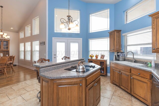 kitchen featuring black electric cooktop, a center island, a notable chandelier, sink, and pendant lighting