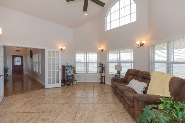 tiled living room featuring a towering ceiling and ceiling fan with notable chandelier