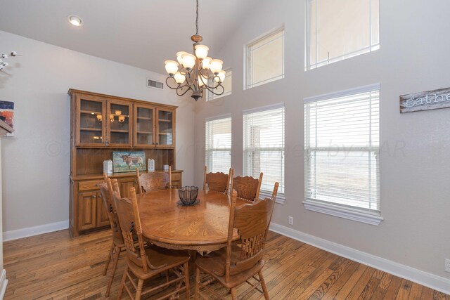 dining area featuring a chandelier, vaulted ceiling, and hardwood / wood-style flooring