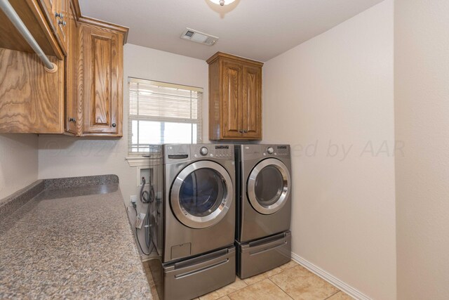 laundry area featuring cabinets, light tile patterned floors, and independent washer and dryer