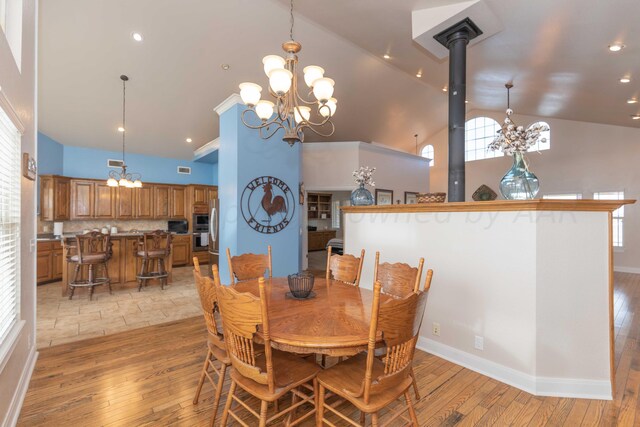 dining room with an inviting chandelier, light wood-type flooring, and a wood stove