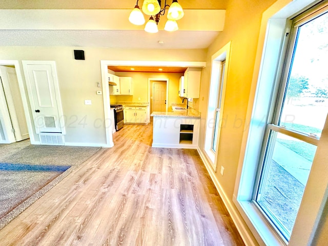222 E 5th St, Higgins, TX 79046 - unfurnished living room with light wood-style floors, a chandelier, baseboards, and a sink