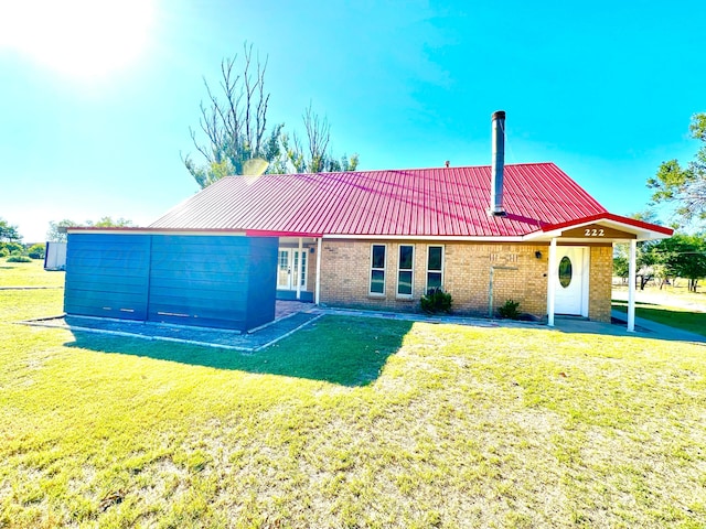 222 E 5th St, Higgins, TX 79046 - rear view of property with brick siding, a lawn, and metal roof