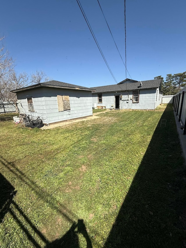 rear view of property featuring fence and a lawn