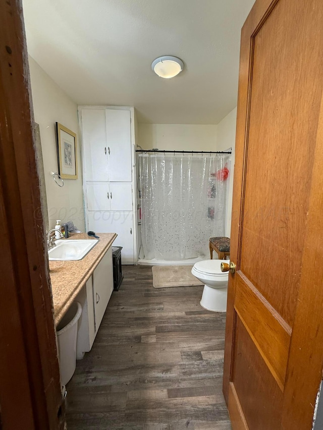 full bathroom with toilet, wood finished floors, vanity, and curtained shower