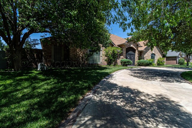 7402 Park Ridge Dr, Amarillo, TX 79119 - obstructed view of property with a front lawn, brick siding, and curved driveway