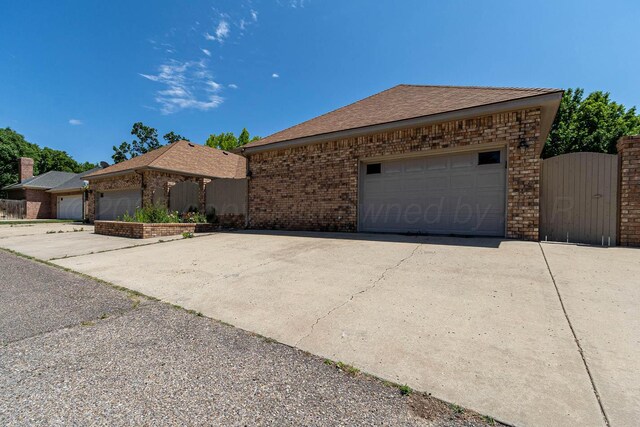 7402 Park Ridge Dr, Amarillo, TX 79119 - ranch-style home featuring a garage, brick siding, a gate, and roof with shingles