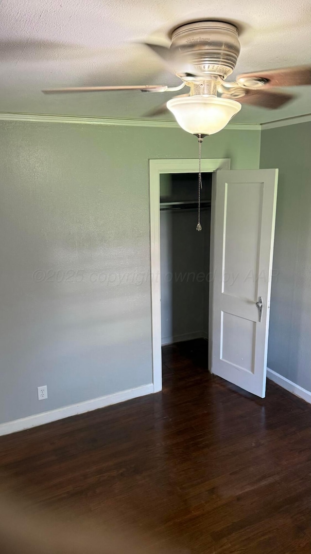 unfurnished bedroom with wood finished floors, a closet, ornamental molding, baseboards, and a ceiling fan