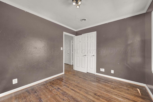 unfurnished room with wood finished floors, baseboards, and crown molding