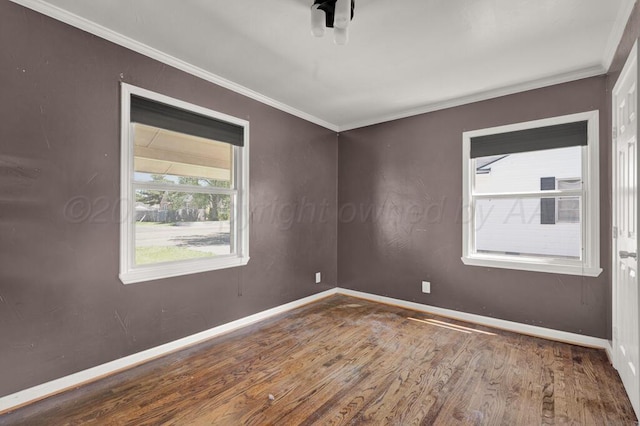 unfurnished room with wood finished floors, ornamental molding, and baseboards