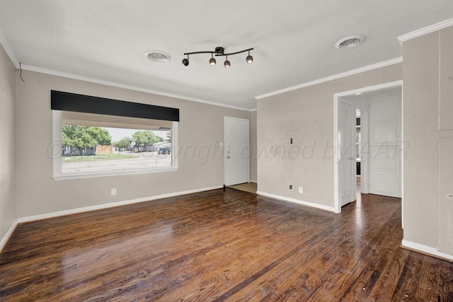 empty room with wood finished floors, ornamental molding, and baseboards