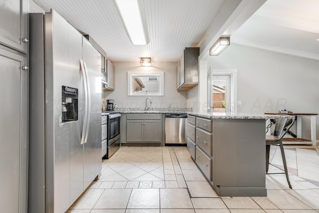 123 Bellaire Ave, Dumas, TX 79029 - kitchen with stainless steel appliances, gray cabinets, light tile patterned floors, and a peninsula
