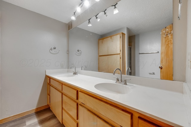 123 Bellaire Ave, Dumas, TX 79029 - bathroom featuring wood finished floors, double vanity, baseboards, and a shower with shower door