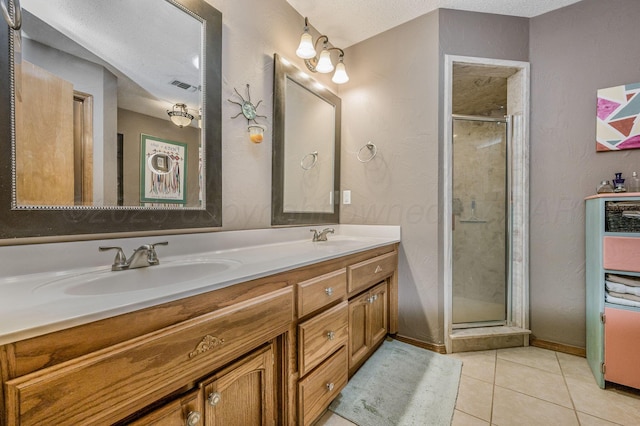 full bath with double vanity, visible vents, tile patterned floors, a shower stall, and a sink