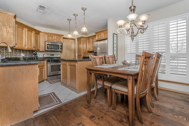 kitchen with pendant lighting, visible vents, decorative backsplash, appliances with stainless steel finishes, and hardwood / wood-style flooring