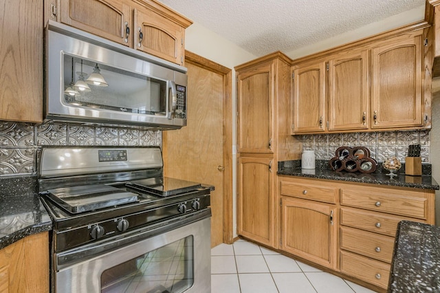 kitchen with light tile patterned floors, appliances with stainless steel finishes, brown cabinets, and tasteful backsplash