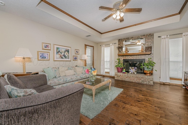 living room featuring a fireplace, crown molding, a raised ceiling, a textured ceiling, and hardwood / wood-style floors