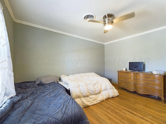 bedroom with crown molding, hardwood / wood-style floors, and ceiling fan