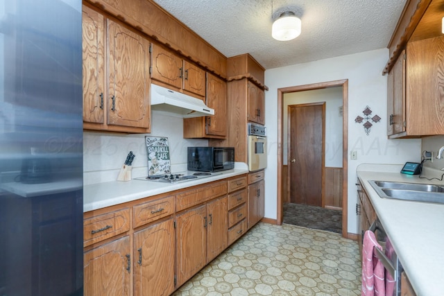 kitchen featuring light countertops, a sink, light floors, under cabinet range hood, and white appliances