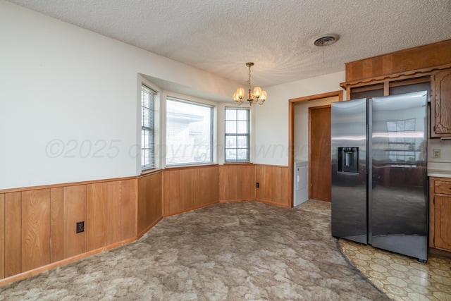 kitchen featuring a wainscoted wall, a textured ceiling, carpet, stainless steel fridge with ice dispenser, and an inviting chandelier