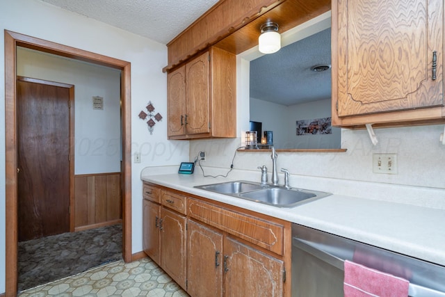 kitchen with a sink, light countertops, dishwasher, and a textured ceiling