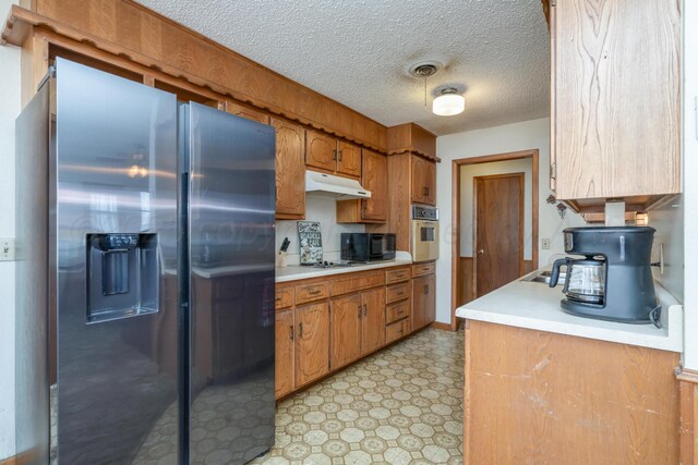 kitchen with light countertops, light floors, under cabinet range hood, and appliances with stainless steel finishes