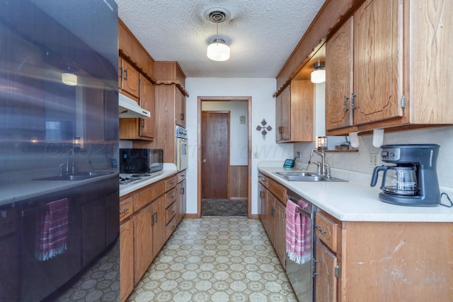 kitchen featuring light countertops, white appliances, under cabinet range hood, a sink, and brown cabinetry